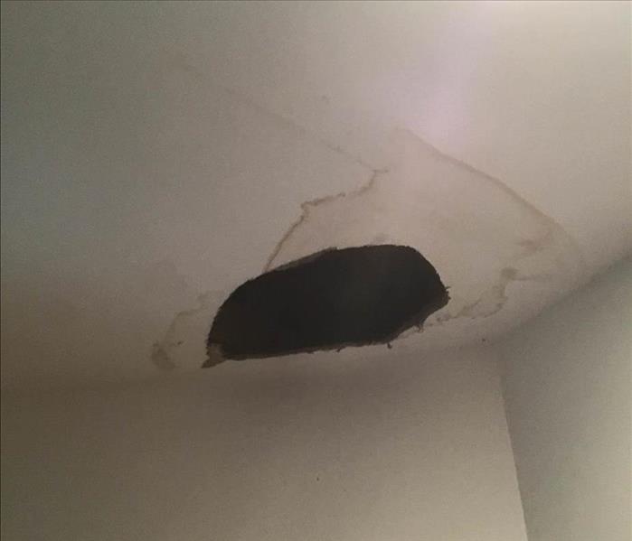 Hole in ceiling with wet stains surrounding it.